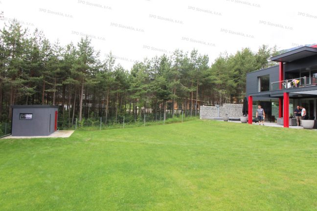 Záhradný domček v tmavo-sivej omietke pri modernom rodinnom dome