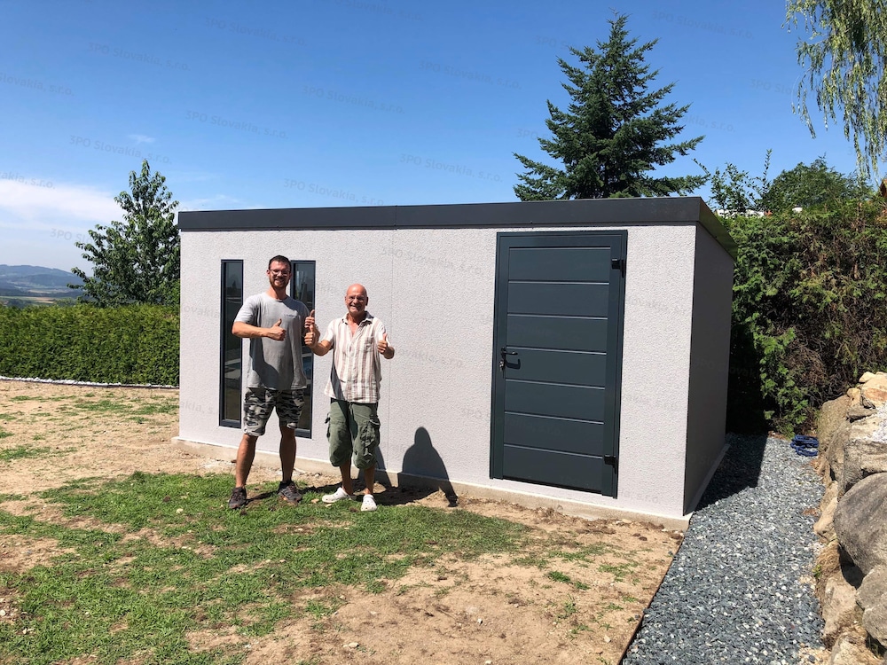 Spokojný zákazník pred montovaným záhradným domčekom v svetlo-sivej omietke