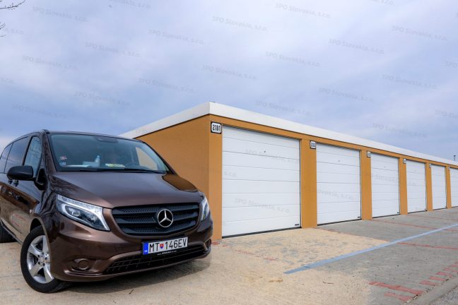 Radová garáž pre 7 automobilov v žltej omietke s bielymi bránami Hormann