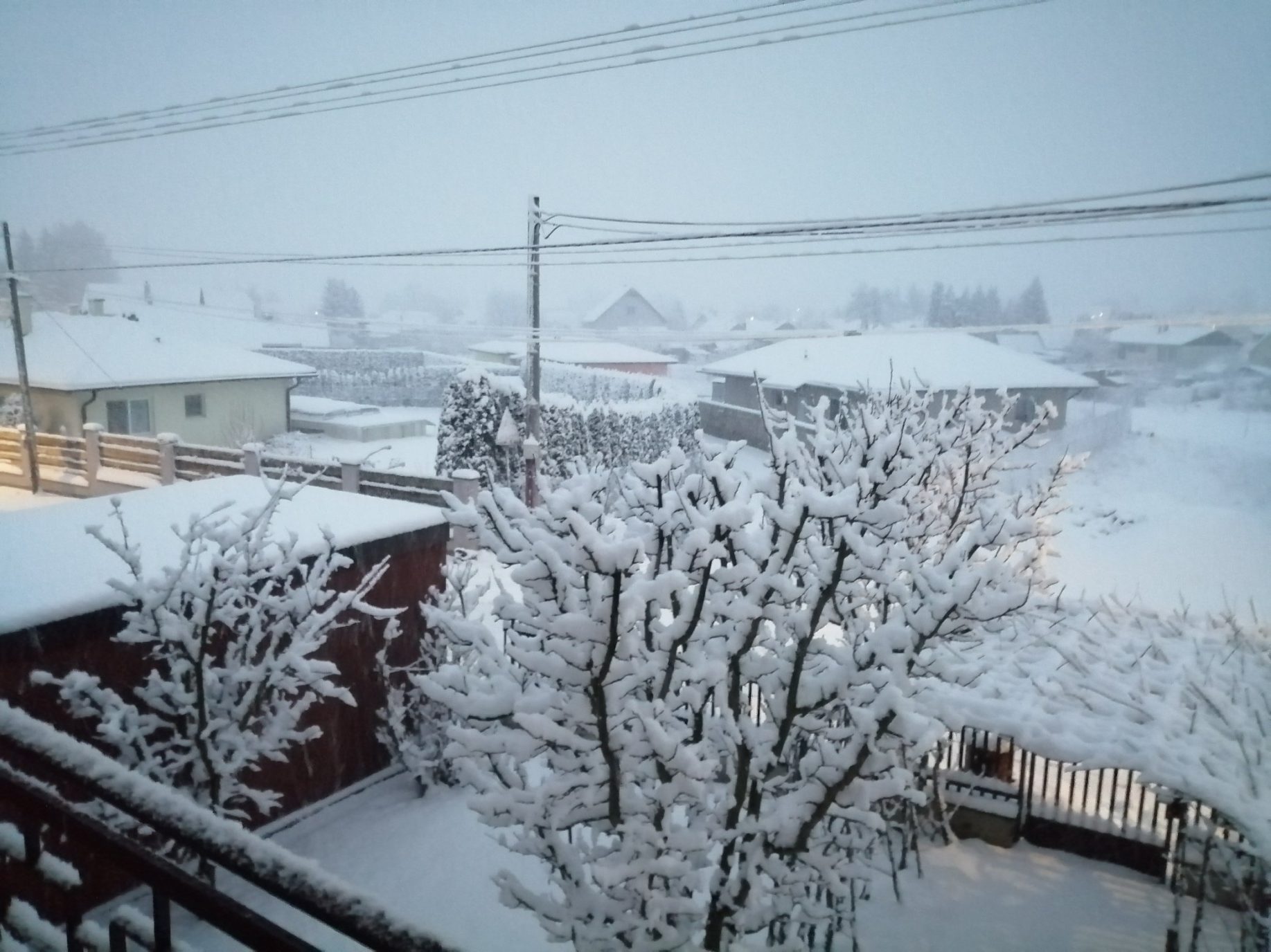 Pohľad z balkóna na zasneženú garáž a záhradu