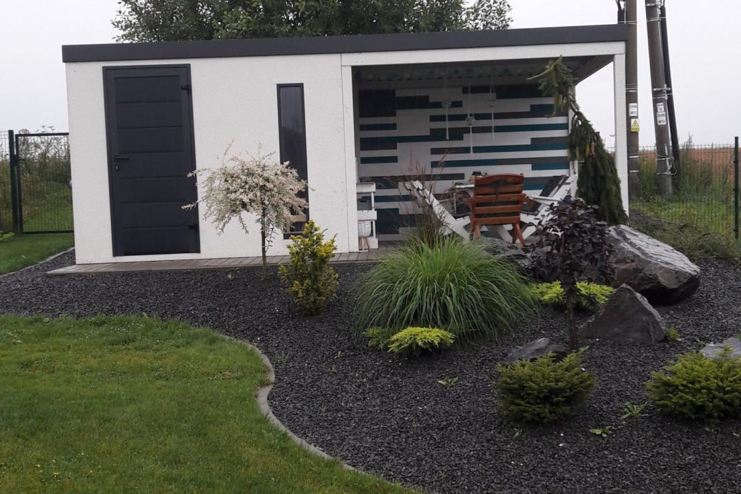 Biely záhradný domček s prestrešením za záhradkou