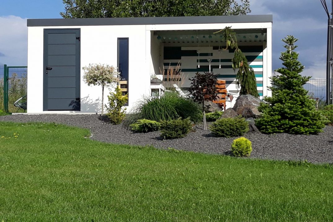 Predná časť bieleho domčeka s prestrešením za záhradkou