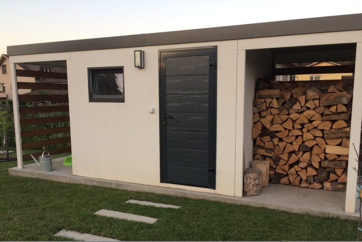 Biely záhradný domček s drevom pod pravým prestrešením