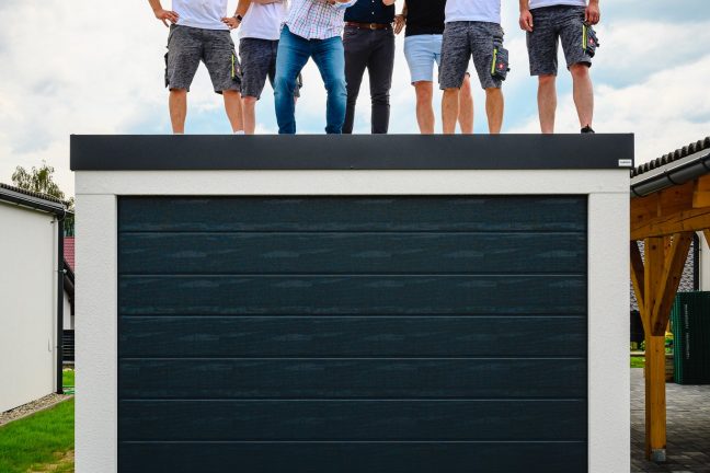 Chlapi stojaci na garáži pre jedno auto