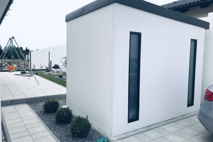 Biely záhradný domček pri hojdačke.