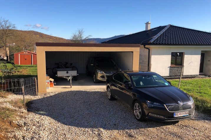 Auto pred otvorenou garážou s autom a bicyklami