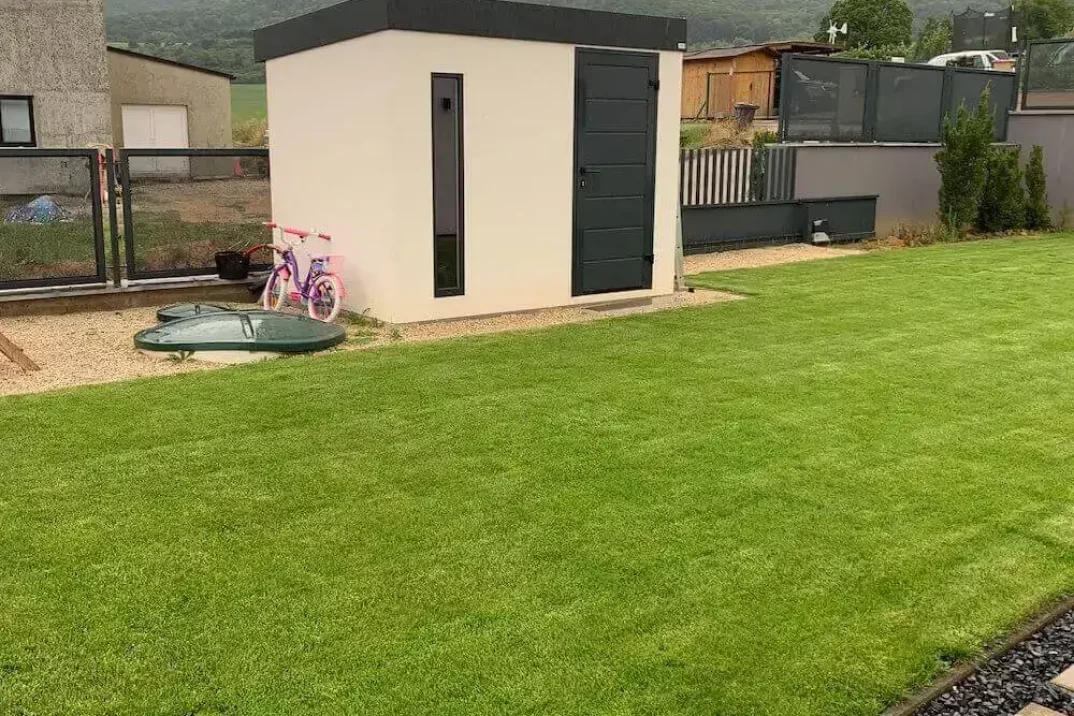 Ružový detský bicykel opretý o záhradný domček v bielej omietke