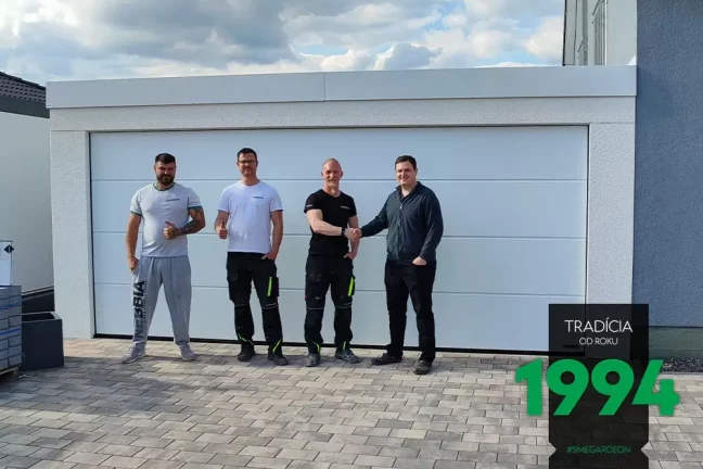 Spokojný zákazník spolu s montážnikmi pred dvojgarážou