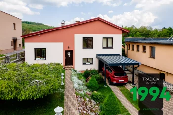 Červené auto pod prístreškom pri dome