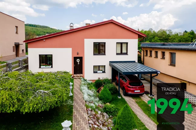 Červené auto pod prístreškom pri dome