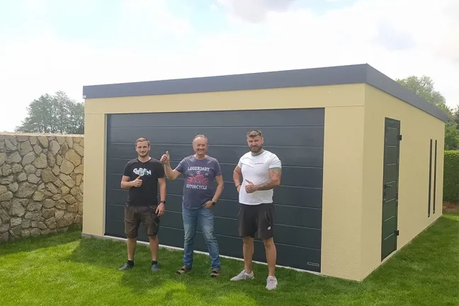 Montážnici so zákazníkom pred žltou garážou na záhrade