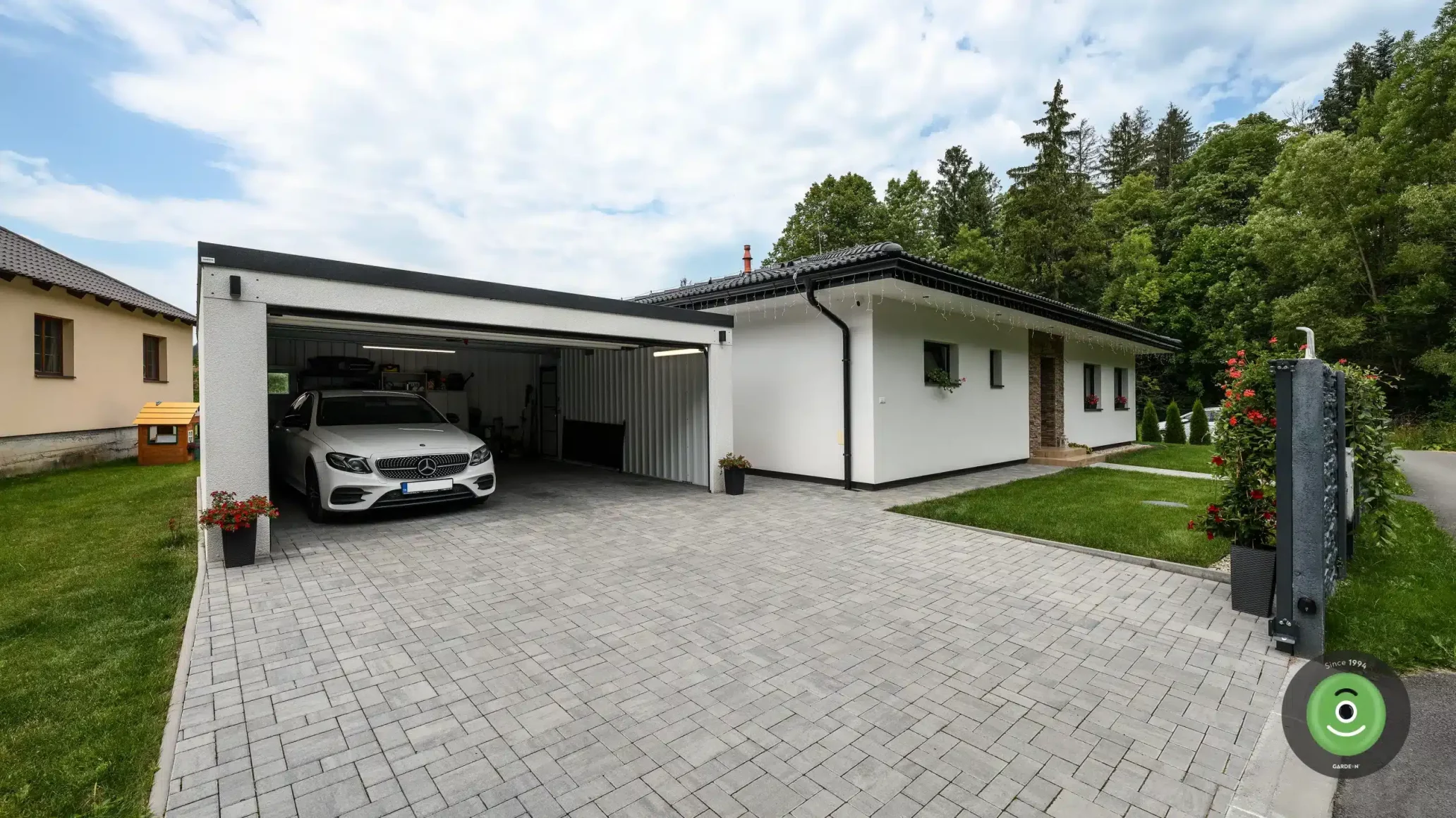 Biela GARDEON garáž s pultovou strechou na zámkovej dlažbe.