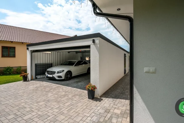 Veľká biela garáž pre auto s posúvnou sekcionálnou bránou.