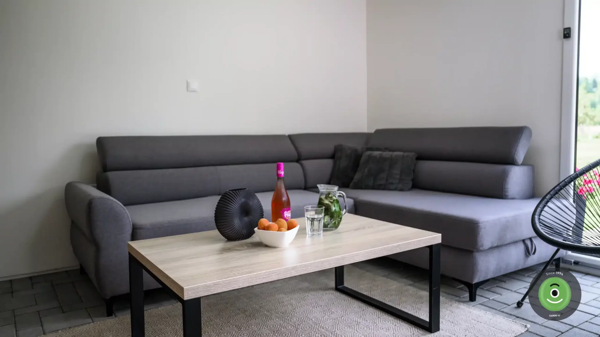 Tmavá pohovka v letnej obývačke v GARDEON domčeku.