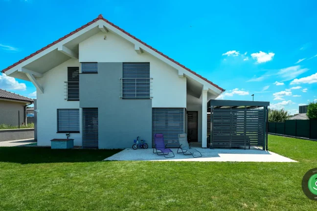 Bielo-sivý rodinný dom s montovanou čiernou pergolou.