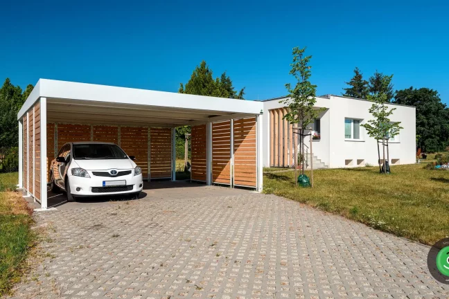 Biely prístrešok GARDEON s bielym autom vo vnútri na záhrade.