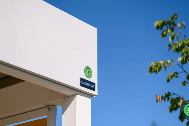 Detail na logo firmy GARDEON umiestnený na bielej atike prístrešku.