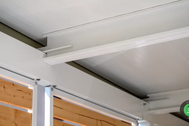 Detail bielych nosníkov pod izolovanou strechou na prístrešku