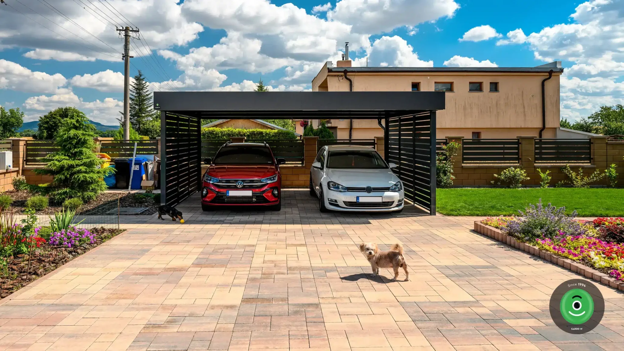 Prístrešok z ocele s čiernou strechou a výplňou pri záhrade s kvetmi.