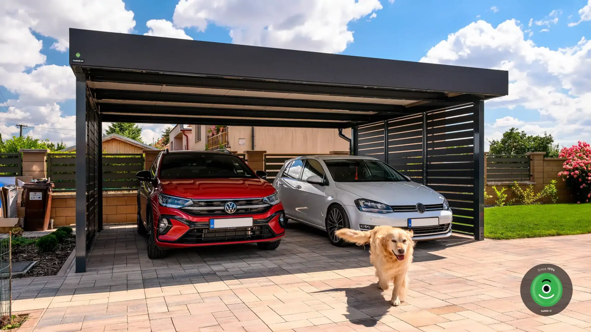 Oceľový prístrešok pre dve autá s červeným a bielym autom vo vnútri.