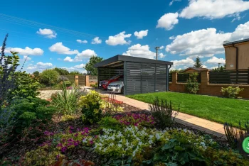 Prístrešok s čiernou strechou a čiernou výplňou pri záhrade.