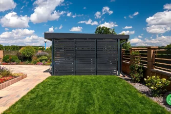 Čierna kovová výplň na prístrešku v záhrade s farebnými kvietkami.