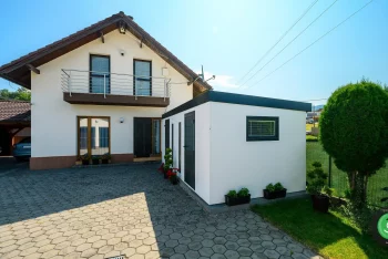 Záhradný domček s bielymi stenami pri záhrade s domom.