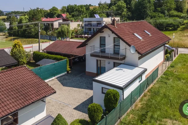 Domček s bielou izolovanou strechou na okrúhlej zámkovej dlažbe.