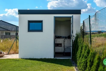 Malý biely záhradný domček s čiernou atikou.