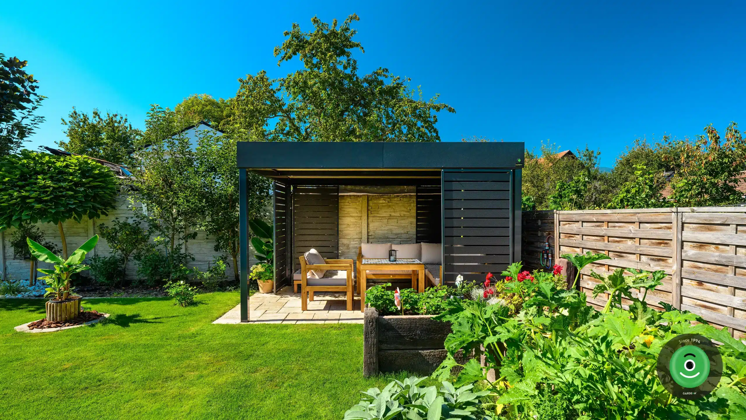 Gardeon pergola v pestrej záhrade s kvetinovými záhonmi