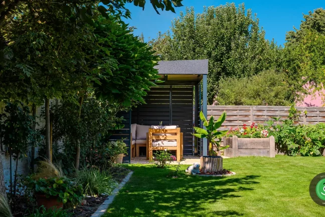 Gardeon pergola s posedením obklopená stromami a kvetmi