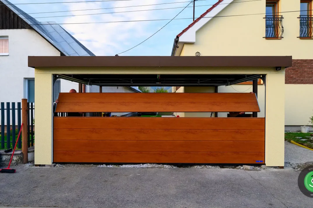 Hnedá sekcionálna brána osadená do prístrešku pre dve autá