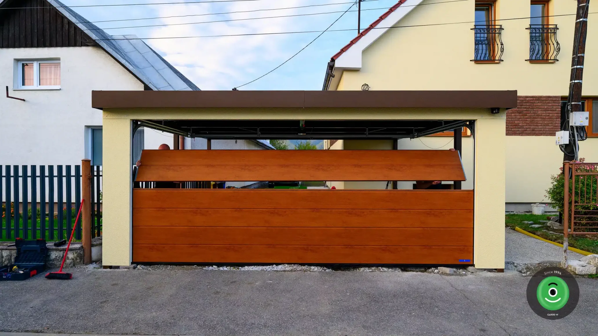 Hnedá sekcionálna brána osadená do prístrešku pre dve autá