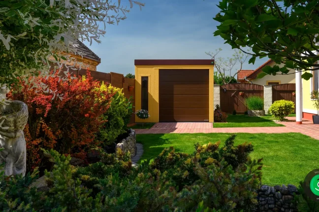 Garáž so žltou omietkou v okolí krásnej zelene