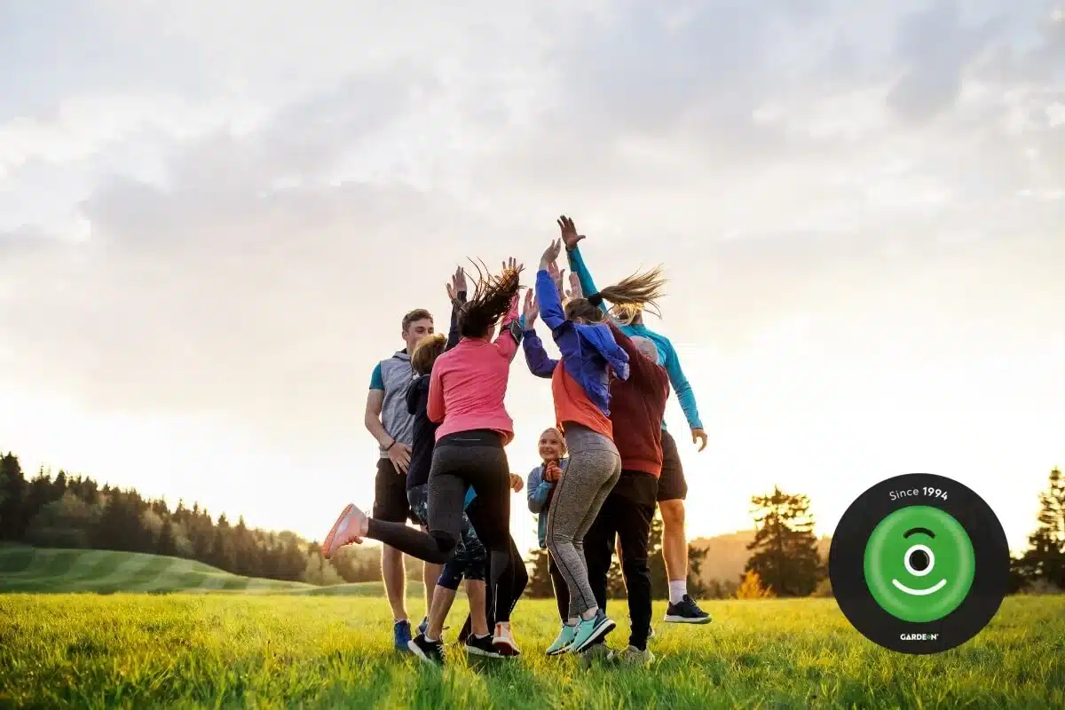 Skupina priateľov radostne skáče na lúke.