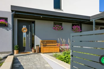 Malý prístrešok pred dverami s drevenou lavičkou na sedenie