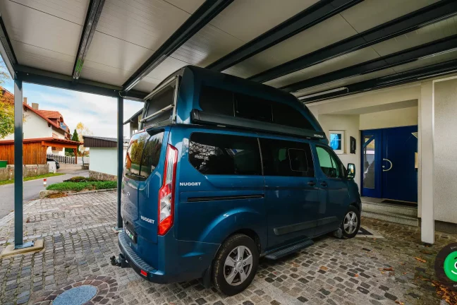 auto pod prístreškom pred vchodovými dverami