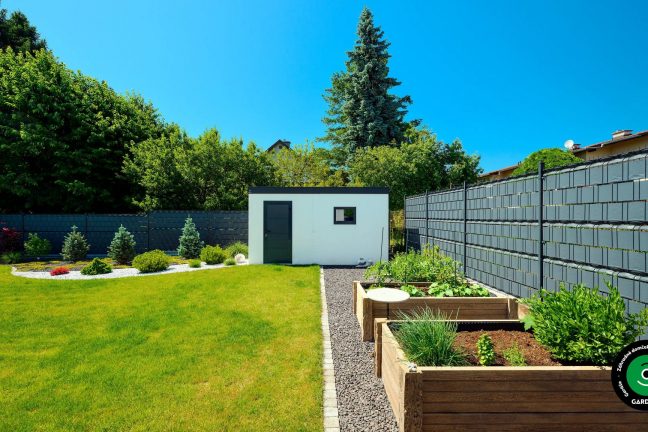 Svetlý záhradný domček pod korunami stromov.