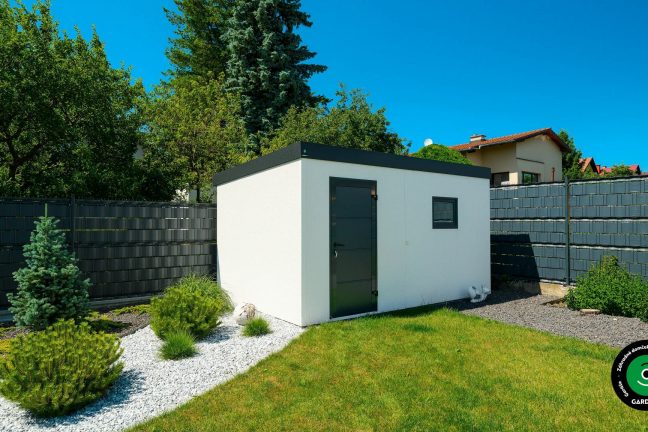 Záhradný domček v bielej, medzi trávou a stromami.