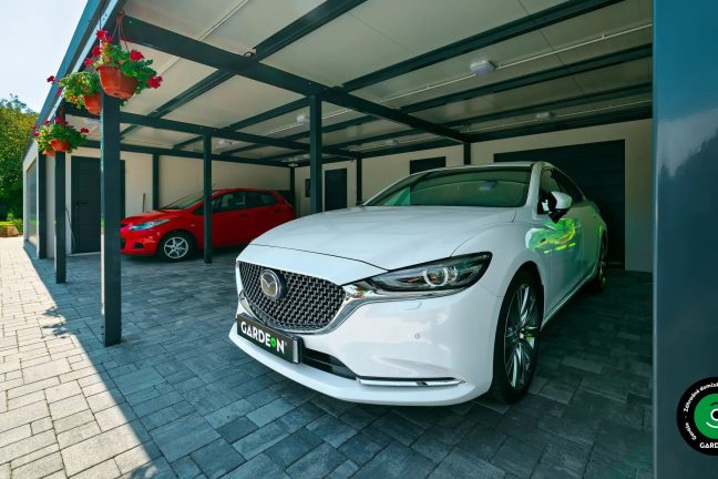 Atypická stavba garáže s dvojitou bránou a veľkým prístreškom.