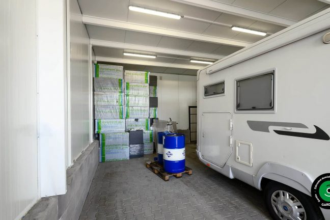 Vnútro garáže s parkovaným autom a uskladneným náradím.