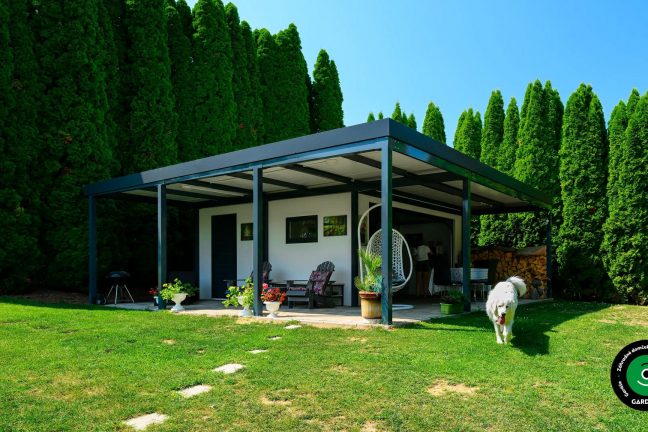 Záhradný domček s garážovou bránou a prístreškom na sedenie.