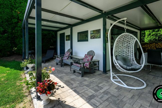 Záhradný domček s prístreškom poskytujúcim tieň pre letné posedenie.