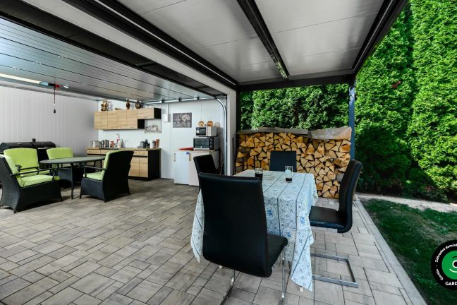 Moderný domček s pultovou strechou a letnou kuchynkou vo vnútri.