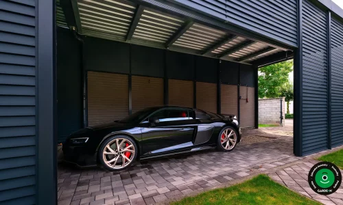 Luxusný čierny športiak zaparkovaný pod kovovým prístreškom.