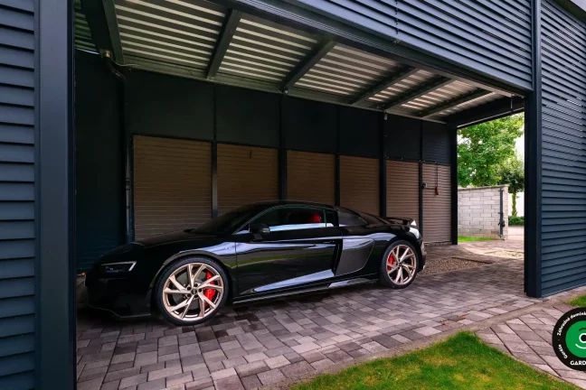 Luxusný čierny športiak zaparkovaný pod kovovým prístreškom.