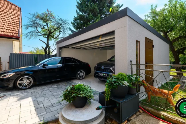 Auto vychádza z modernej garáže na vydláždený dvor.