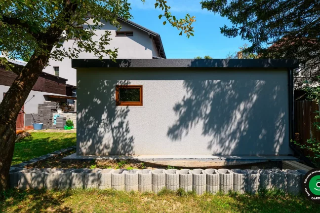 Bočný pohľad na garáž s oknom a záhradou.