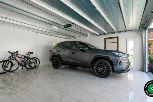 Priestranný interiér garáže s autom a bicyklami.