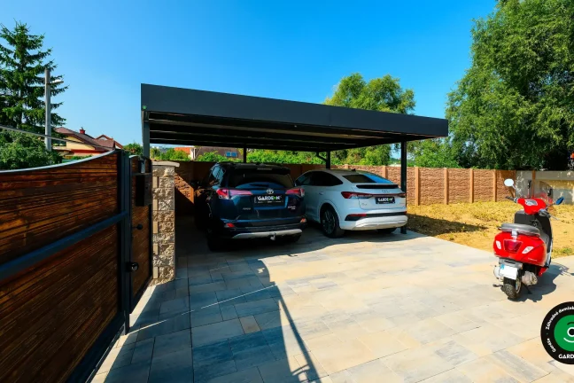 Moderný prístrešok pre dve autá s tmavou strechou a vydláždeným dvorom.